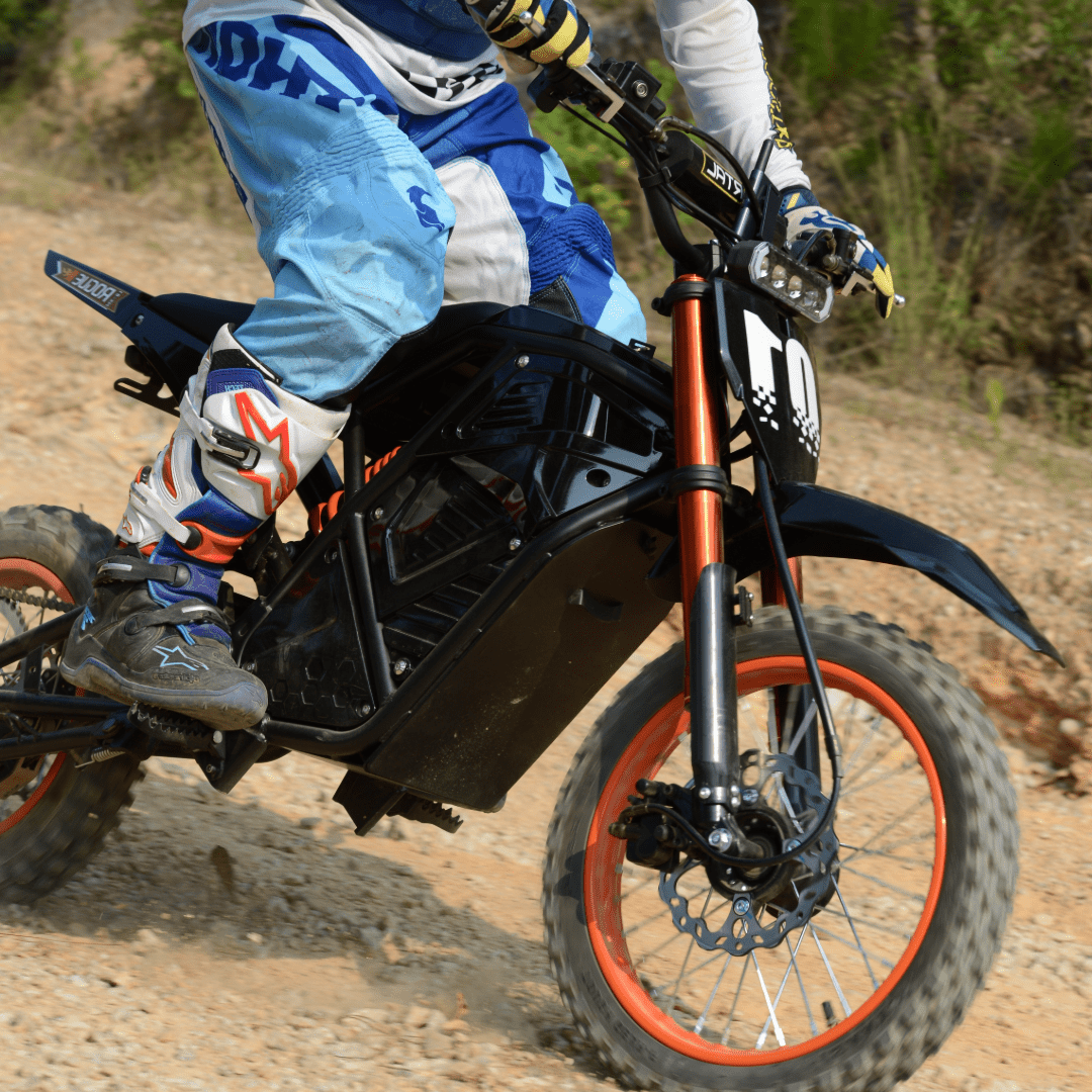 Rider accelerating Rogue MX-01 electric dirt bike on rough rocky path, showcasing 3000W motor power