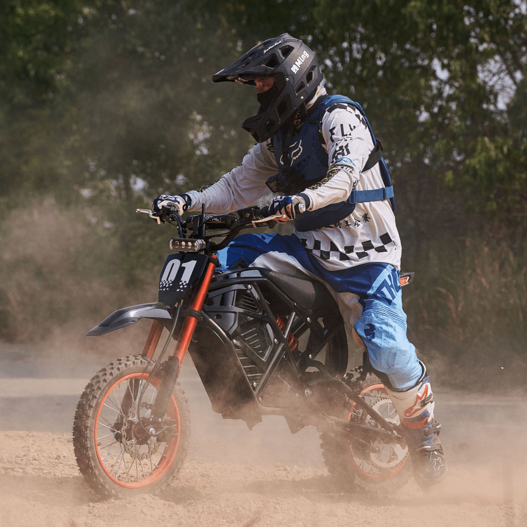 Rider on Rogue MX-01 3000W electric dirt bike drifting on dusty off-road trail with hydraulic disc brakes