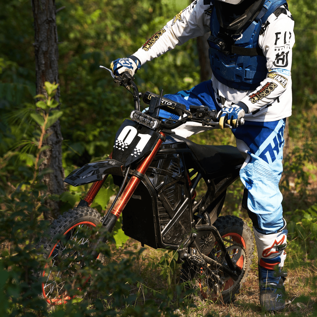 Rogue MX-01 electric dirt bike with 3000W mid-drive motor ridden through forest trail, off-road adventure
